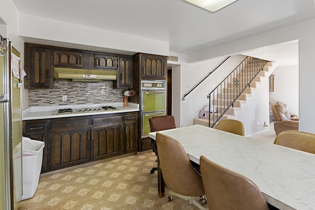 kitchen with backsplash, double oven, stainless steel gas cooktop, and dark brown cabinetry