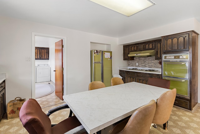 kitchen featuring appliances with stainless steel finishes, tasteful backsplash, light tile floors, washer / dryer, and dark brown cabinetry