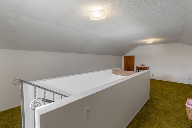 additional living space featuring a textured ceiling, dark carpet, and vaulted ceiling