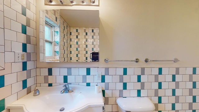 bathroom with sink, toilet, and tile walls