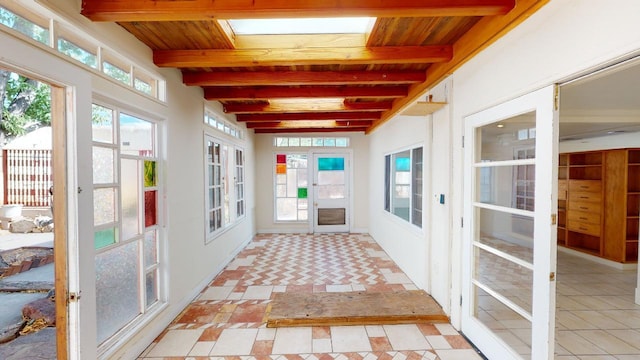 unfurnished sunroom with wooden ceiling, beam ceiling, french doors, and a healthy amount of sunlight