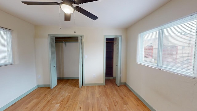 unfurnished bedroom featuring multiple closets, ceiling fan, and light wood-type flooring