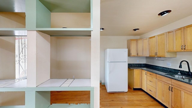 kitchen with light hardwood / wood-style flooring, light brown cabinetry, white fridge, and sink