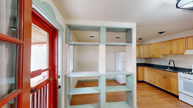 kitchen featuring white appliances, sink, extractor fan, light brown cabinets, and light wood-type flooring