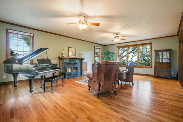 living room with crown molding, a wealth of natural light, a textured ceiling, and light wood-type flooring