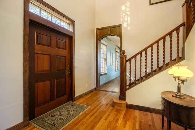 foyer entrance with a towering ceiling, a healthy amount of sunlight, and light hardwood / wood-style flooring