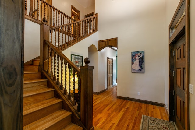 staircase featuring hardwood / wood-style flooring and a towering ceiling