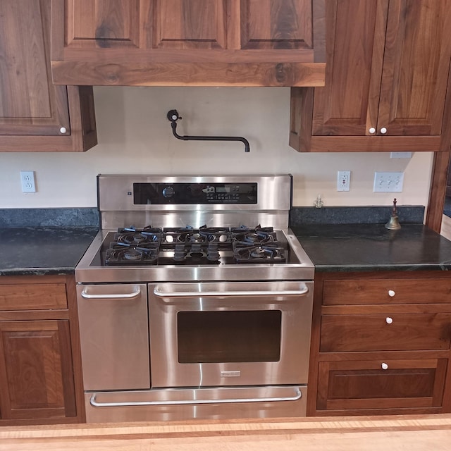 kitchen featuring range with two ovens and dark stone countertops