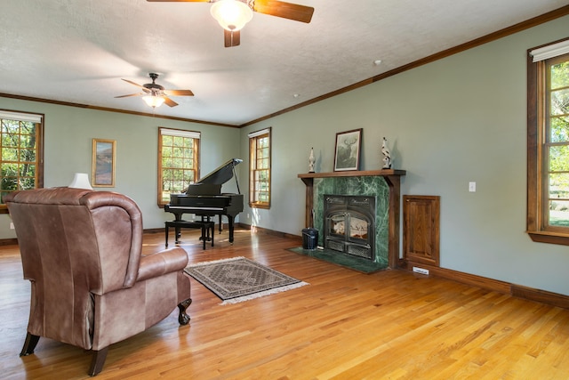 living room with a textured ceiling, wood-type flooring, ornamental molding, and ceiling fan