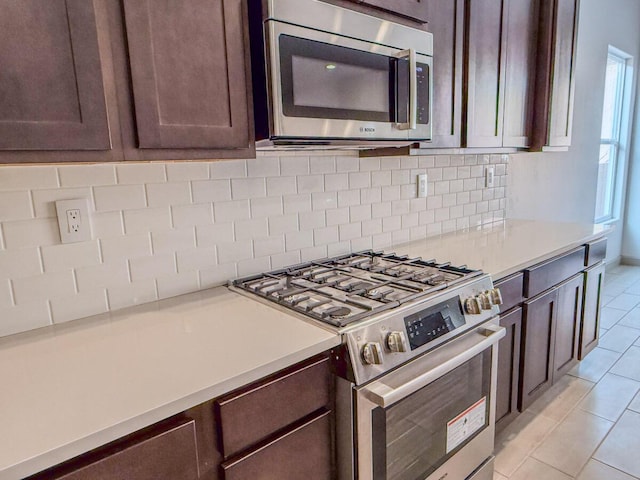 kitchen featuring light tile patterned floors, backsplash, dark brown cabinets, and appliances with stainless steel finishes