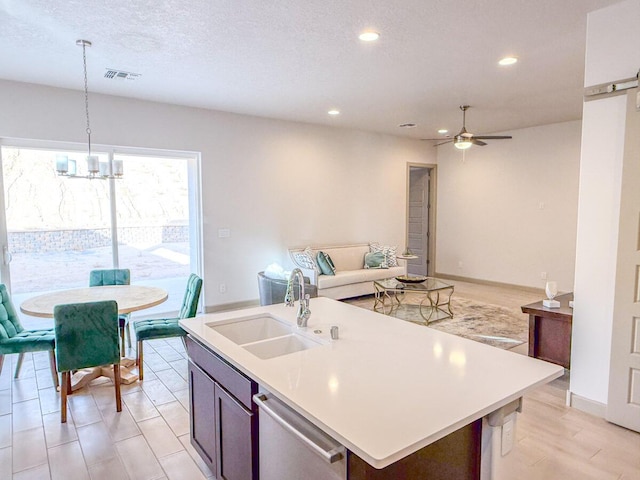 kitchen featuring pendant lighting, sink, an island with sink, stainless steel dishwasher, and a barn door