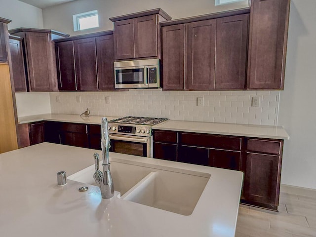 kitchen featuring stainless steel appliances, dark brown cabinets, backsplash, and light hardwood / wood-style floors