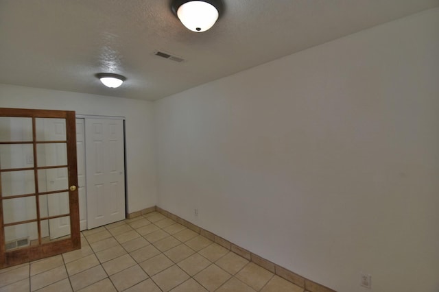 tiled empty room with a textured ceiling