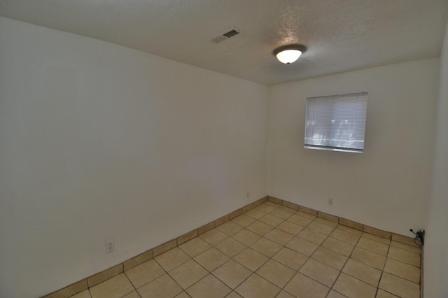 tiled spare room with a textured ceiling