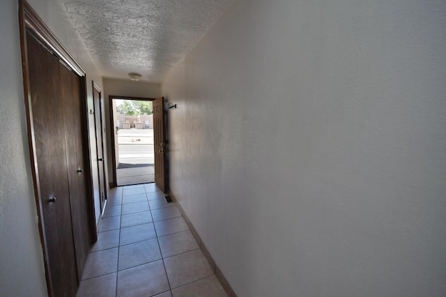 corridor featuring a textured ceiling and light tile patterned flooring