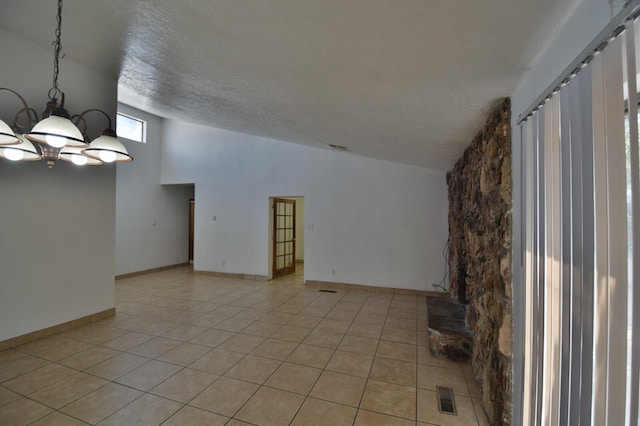 unfurnished living room with a textured ceiling, a chandelier, high vaulted ceiling, and light tile patterned flooring