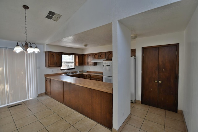 kitchen featuring a notable chandelier, kitchen peninsula, hanging light fixtures, white double oven, and light tile patterned floors