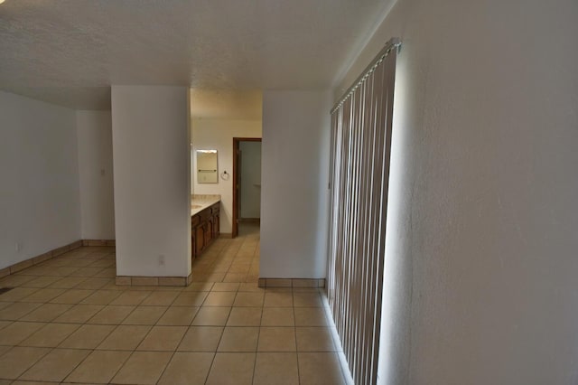 unfurnished room with a textured ceiling and light tile patterned flooring