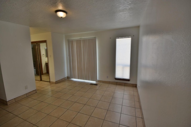 unfurnished room featuring a textured ceiling and light tile patterned floors