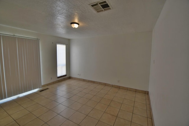 empty room with a textured ceiling and light tile patterned floors