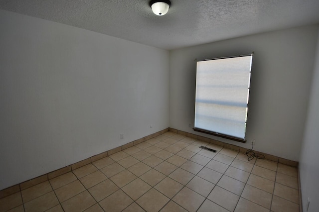 tiled empty room featuring a textured ceiling