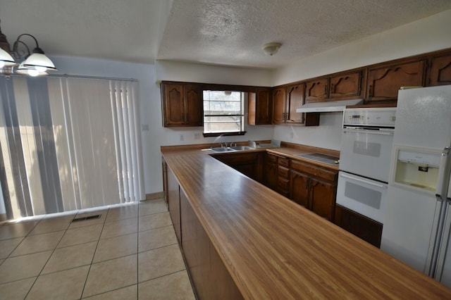 kitchen featuring light tile patterned floors, a textured ceiling, sink, and white appliances