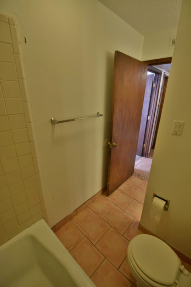 bathroom featuring a bath, tile patterned floors, and toilet