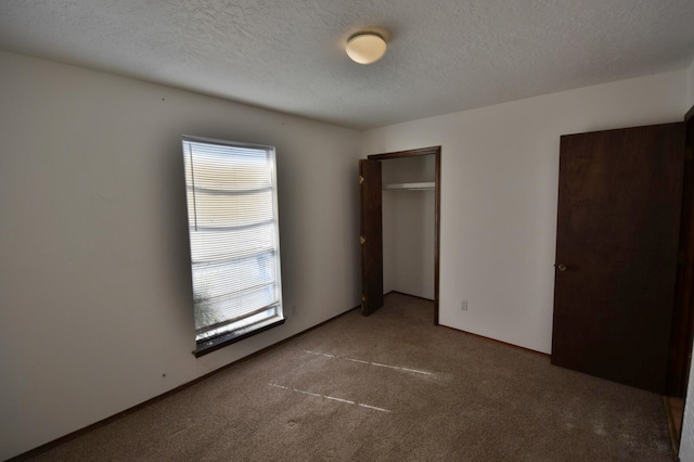 unfurnished bedroom with dark carpet and a textured ceiling