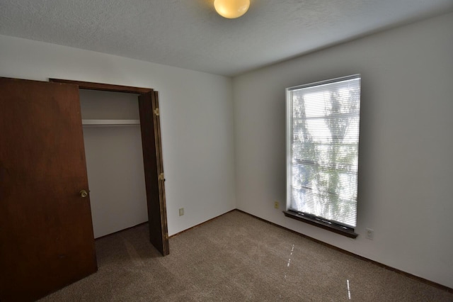 unfurnished bedroom with carpet, a closet, and a textured ceiling