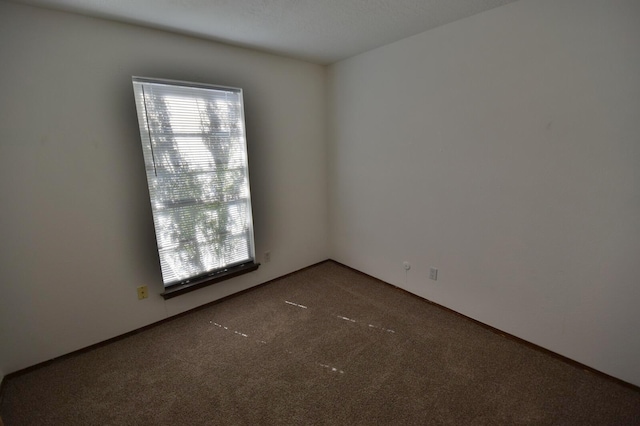 unfurnished room with dark colored carpet