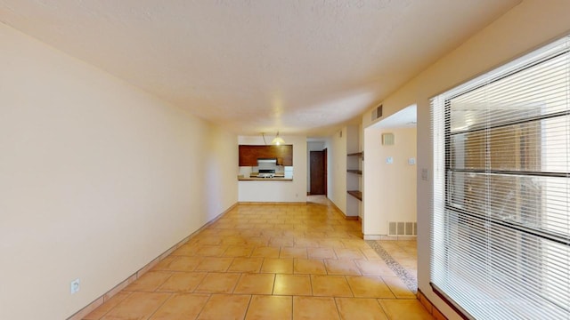 hallway featuring a textured ceiling and light tile patterned floors