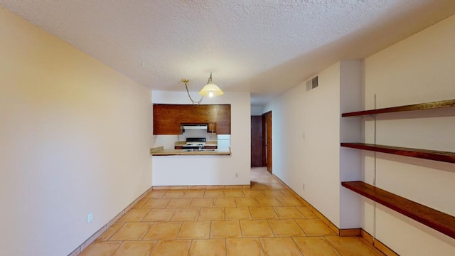 kitchen with light tile patterned flooring, a textured ceiling, decorative light fixtures, range hood, and electric stove