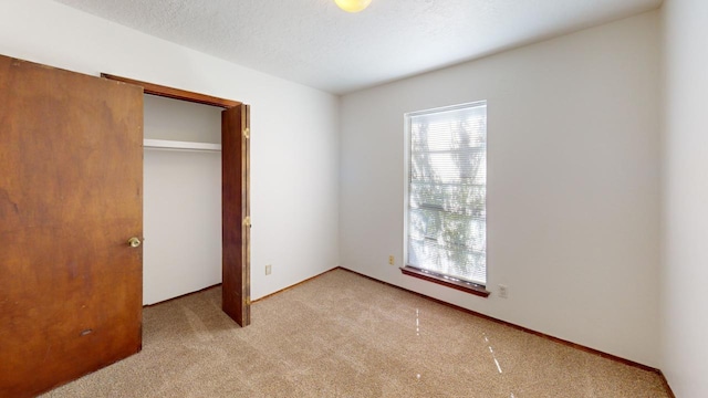 unfurnished bedroom featuring light colored carpet, a textured ceiling, and a closet