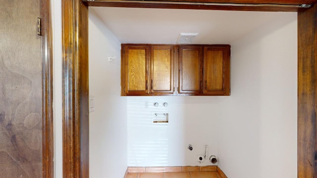 washroom with gas dryer hookup, light tile patterned flooring, washer hookup, and cabinets