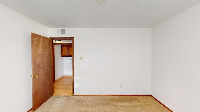 carpeted empty room with a textured ceiling