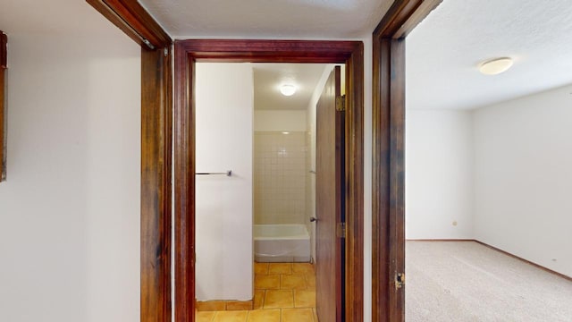 hall with a textured ceiling and light tile patterned flooring