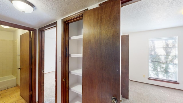 corridor featuring light carpet and a textured ceiling