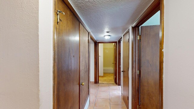 hall featuring a textured ceiling and light tile patterned flooring