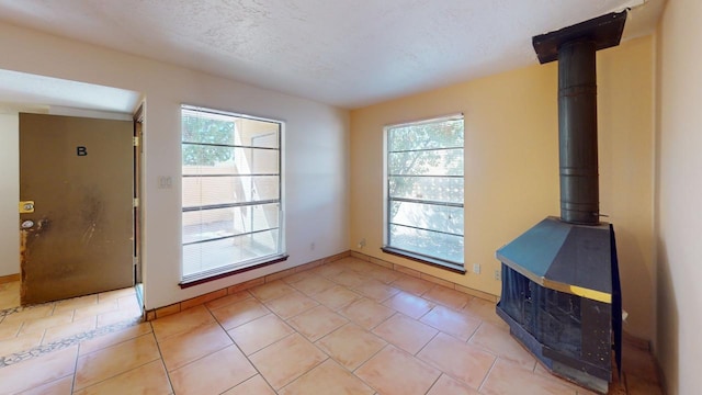 unfurnished living room with a textured ceiling, light tile patterned flooring, and a healthy amount of sunlight