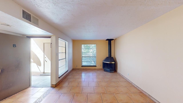 doorway to outside with a wood stove, a textured ceiling, and light tile patterned flooring