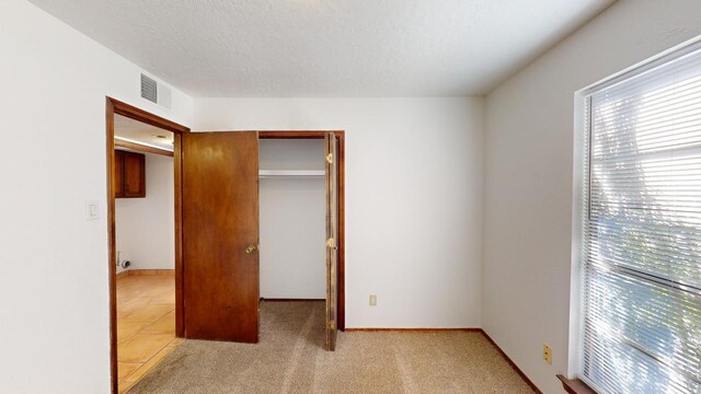 carpeted bedroom with a closet and a textured ceiling