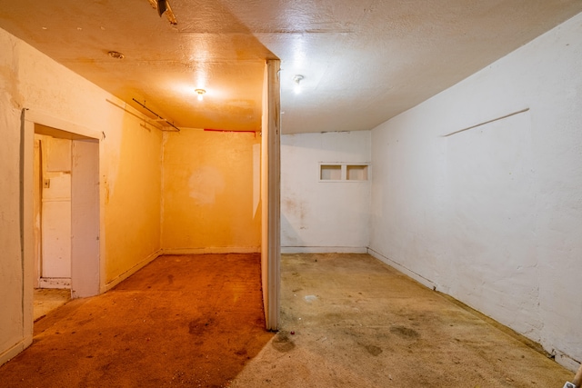 basement featuring light colored carpet and a textured ceiling