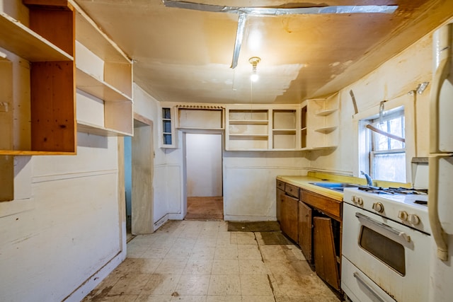 kitchen featuring light tile flooring, sink, and white range with gas cooktop