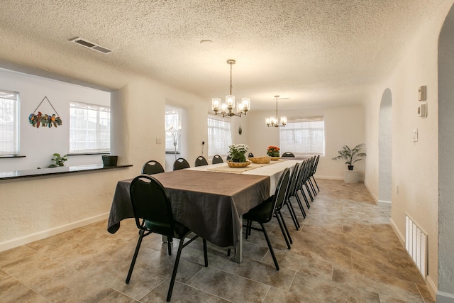 dining space with a textured ceiling and a notable chandelier