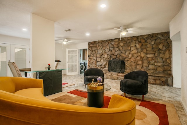 living room with washer and clothes dryer, a large fireplace, ceiling fan, and french doors