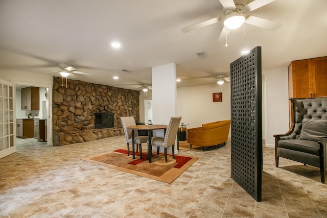 dining space featuring ceiling fan, a fireplace, and french doors