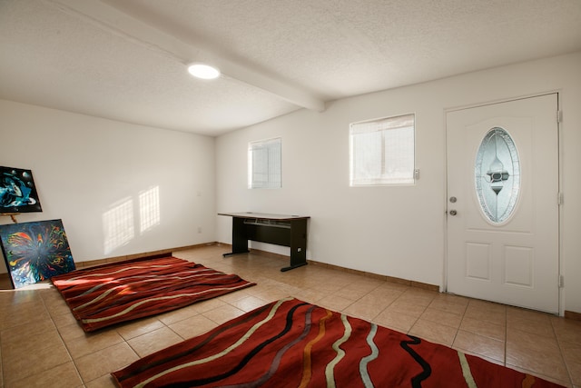 foyer entrance with light tile patterned flooring, a textured ceiling, and vaulted ceiling with beams