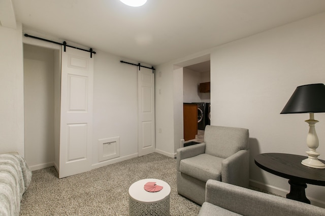 living room featuring washer / clothes dryer, a barn door, and light colored carpet