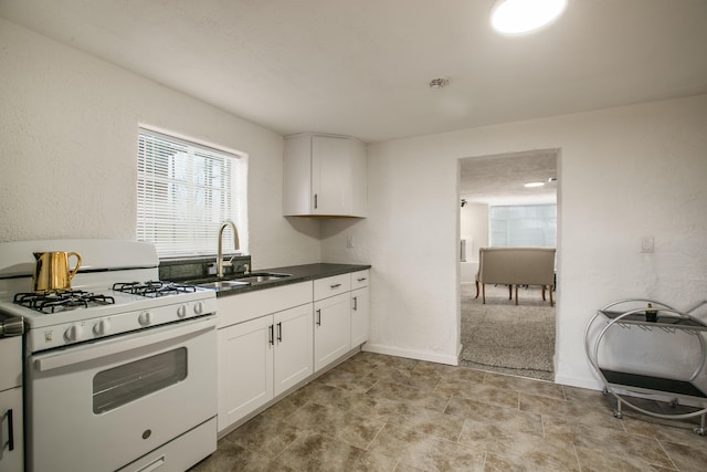 kitchen featuring sink, white cabinets, and gas range gas stove