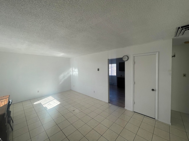 tiled empty room featuring a textured ceiling